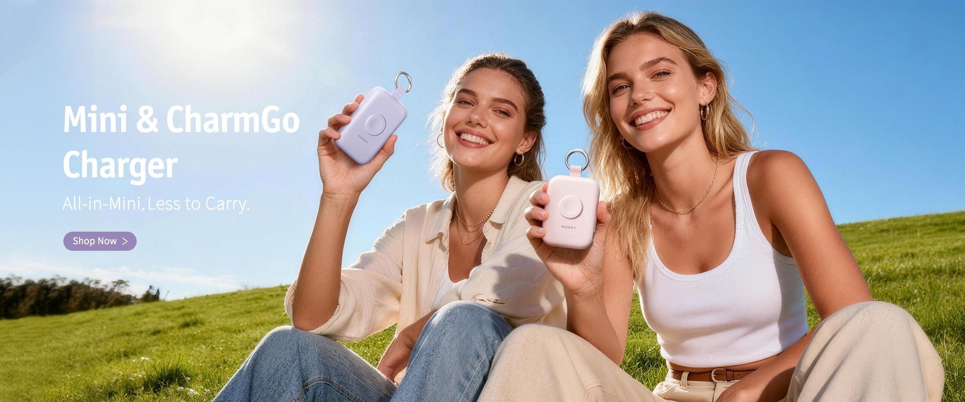 Two women holding Mini & CharmGo chargers with a clear blue sky in the background